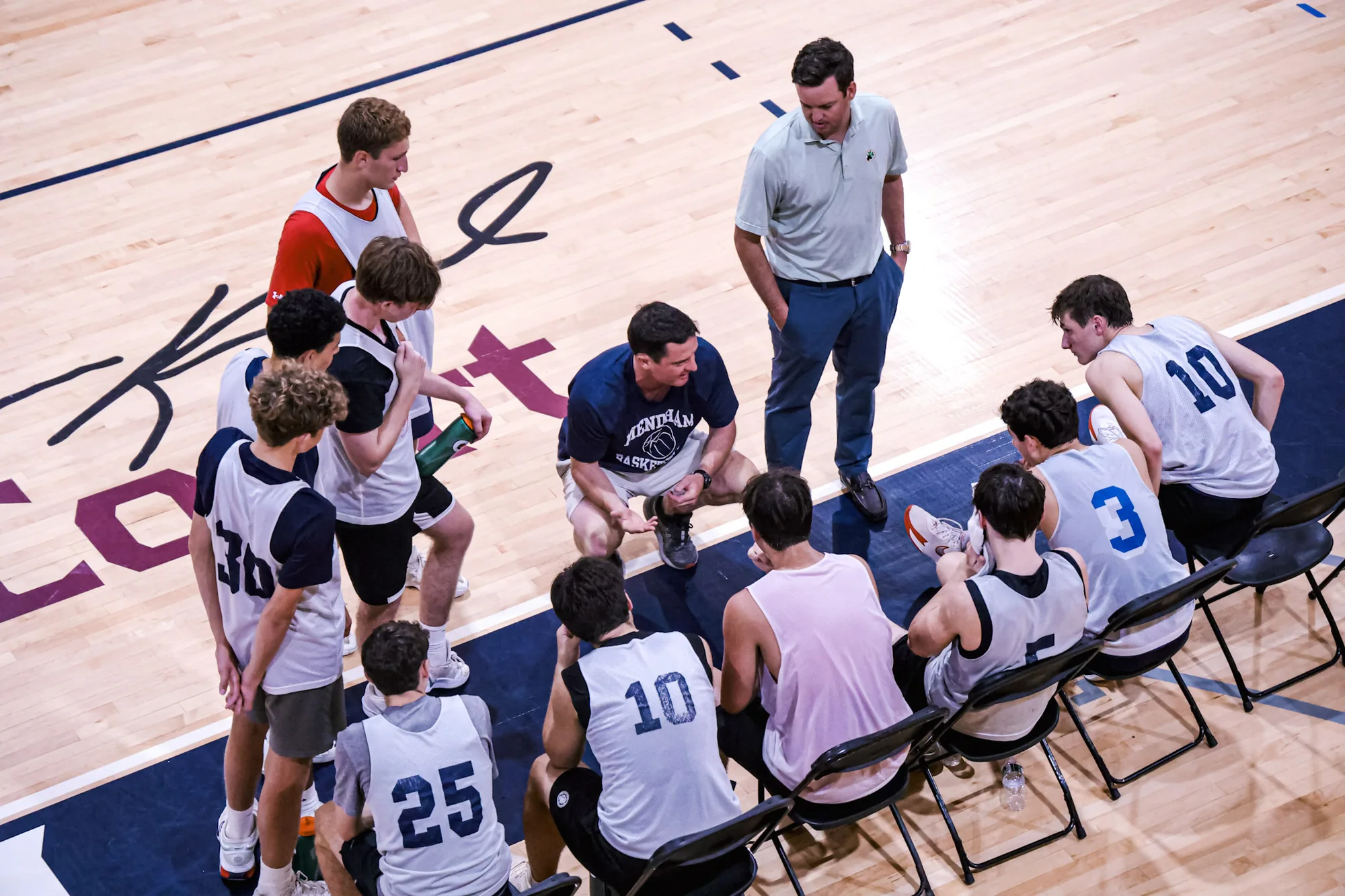 Coaches and players in a timeout huddle on the FDU Madison court